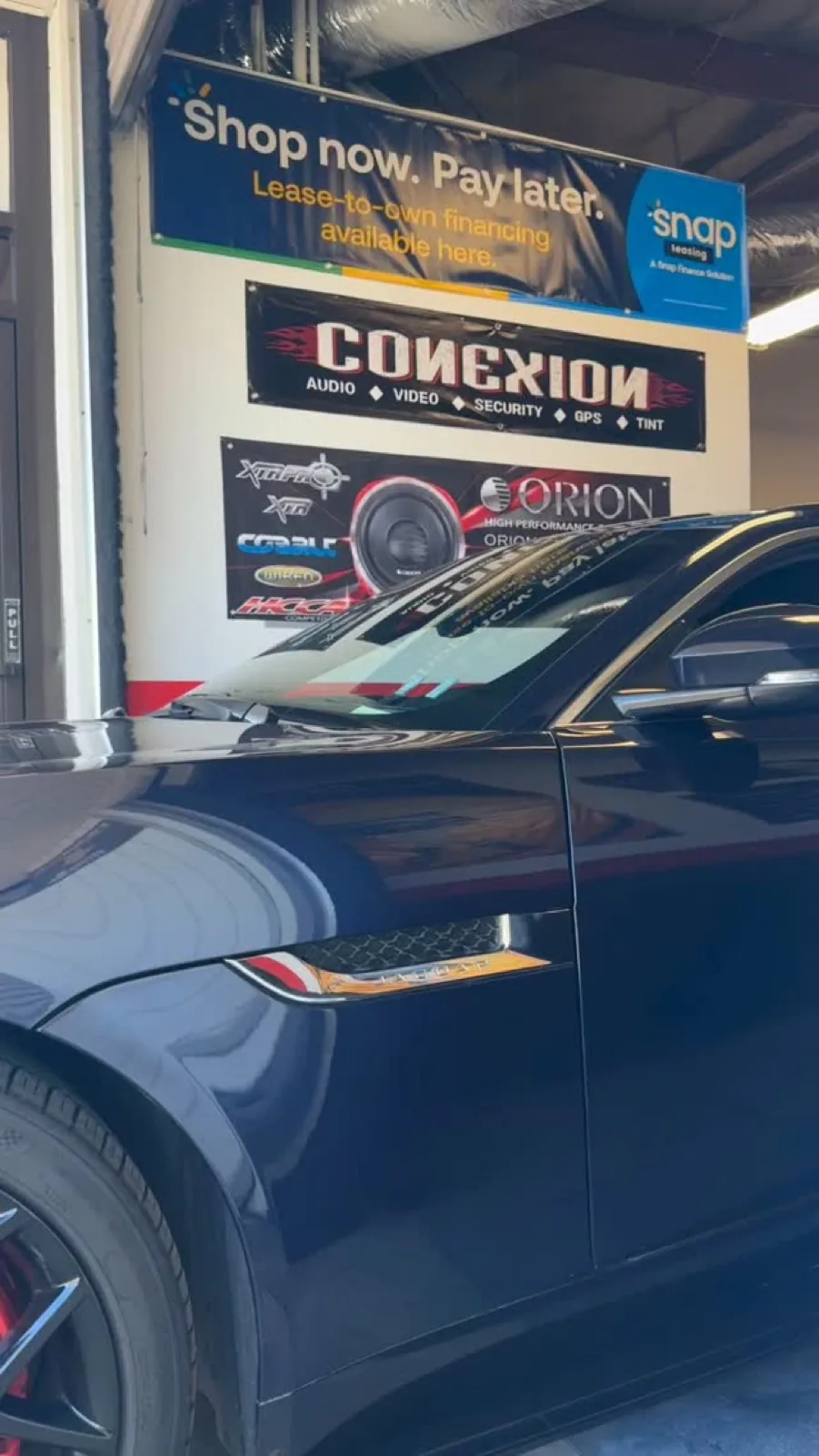 A car in the Conexion bay in Kearny Mesa, under the shop's own signs
