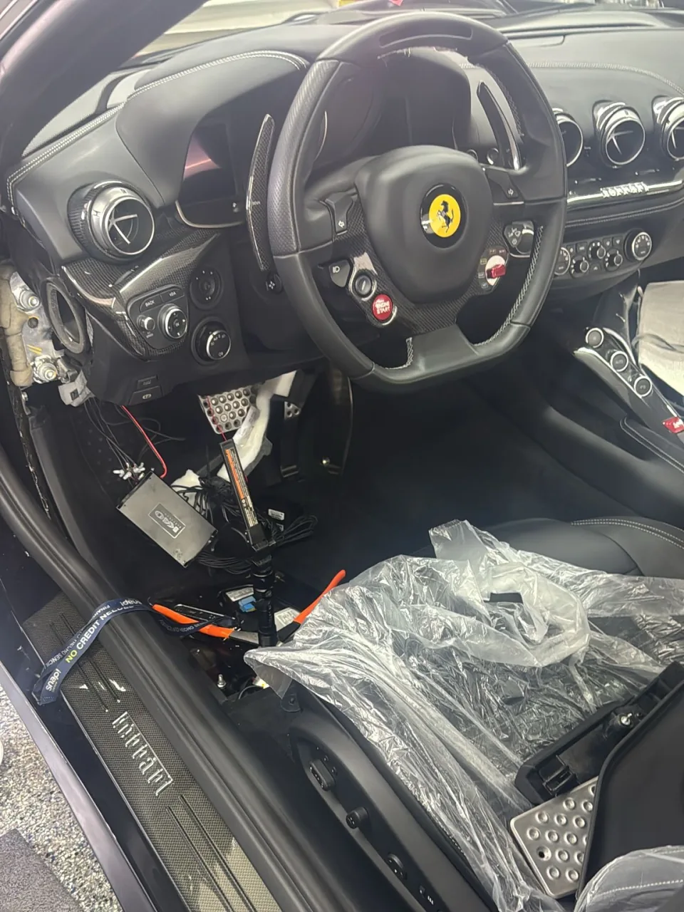 Dash camera wiring being installed in a Ferrari F12 with the trim removed